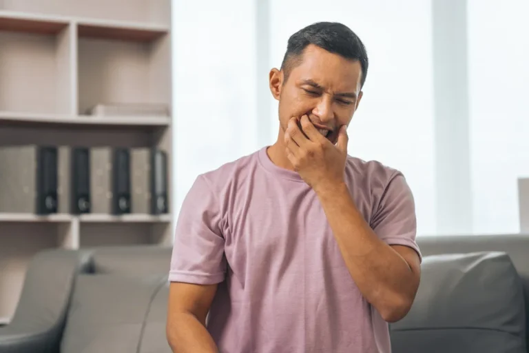 Middle-aged Asian Indian man with gum disease, toothache, wisdom tooth and molar pain. sitting on the sofa